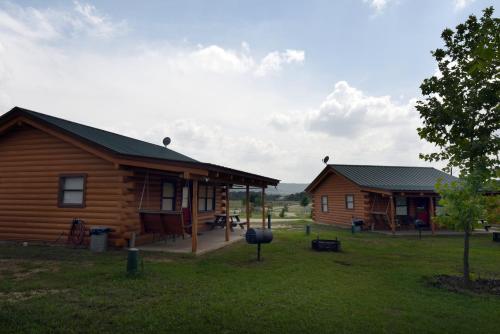 a couple of log homes in a field at River Bluff Cabins in Rio Frio
