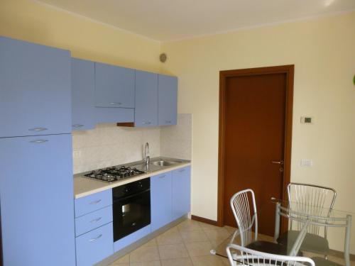 カヴァルカゼッレにあるLa Cornice del Gardaのキッチン(青いキャビネット、テーブル、椅子付)