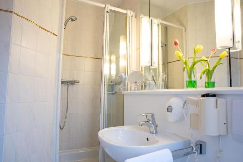 een witte badkamer met een wastafel en een douche bij Hotel Schere in Northeim