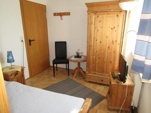 a bedroom with a bed and a table and a chair at Pension Hinter der Düne in Juliusruh