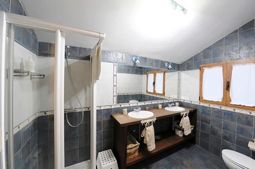 baño de azulejos azules con 2 lavabos y ducha en El Rincon del Labrador en La Santa Espina