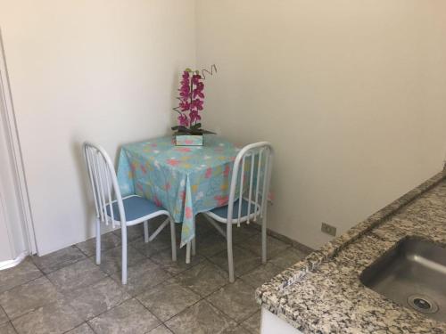 a table with two chairs and a table with a vase on it at Residencias JAC in Paraguaçu Paulista