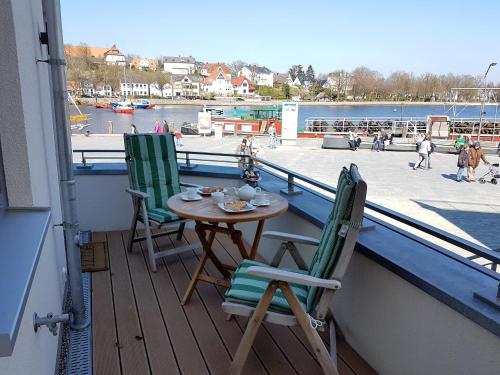 a table and chairs on a balcony with a view of a harbor at Apartment Lütte Bris in Eckernförde