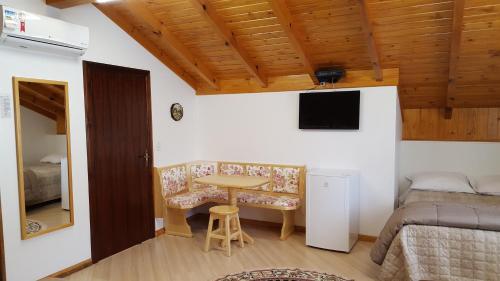 a small room with a table and a bed and a desk at Pousada Pattis in Treze Tílias