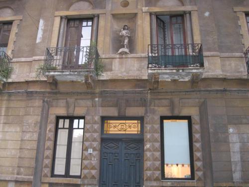 a building with a blue door and windows and a statue at i 2 puttini in Catania
