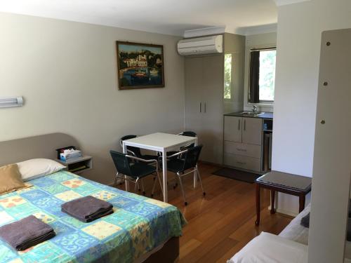 1 dormitorio con cama, mesa y cocina en Palms Oasis Motel, en Coopernook