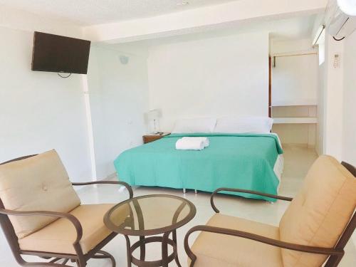 a bedroom with a bed and two chairs and a table at Posada Seven Colours Ocean in Providencia