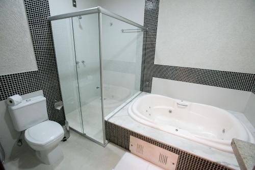 a bathroom with a tub, toilet and sink at Hotel Colombo in Barra do Garças
