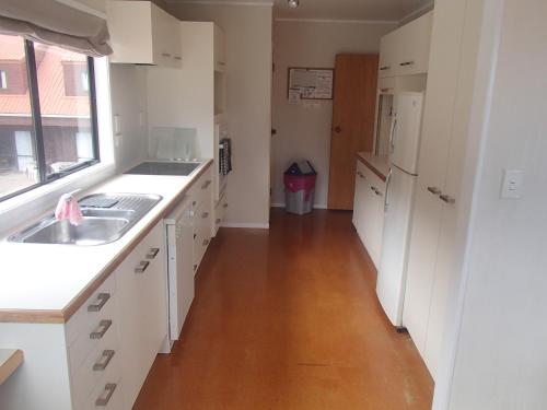 a kitchen with white cabinets and a wooden floor at White Sands in Rangiputa