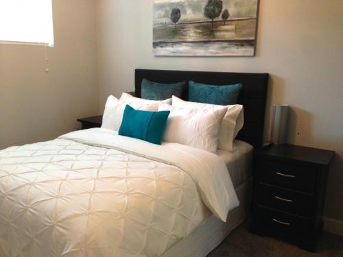 a bedroom with a white bed with blue pillows at Nature's Door Guest Suite in Port Moody
