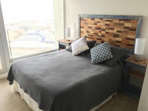 a bedroom with a large bed with a large window at Apartamento en Club Oceano in Coquimbo