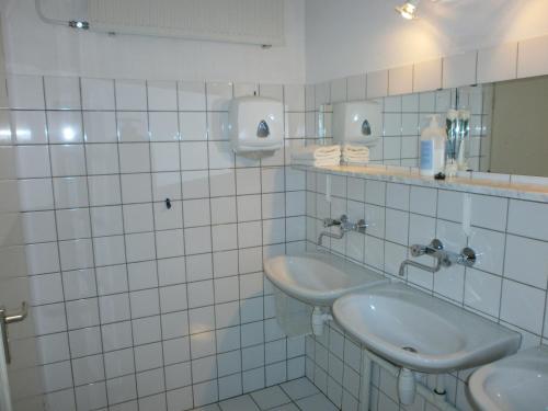 W wyłożonej białymi kafelkami łazience znajdują się 2 umywalki i lustro. w obiekcie Bed & Breakfast Zuidlaren w mieście Zuidlaren