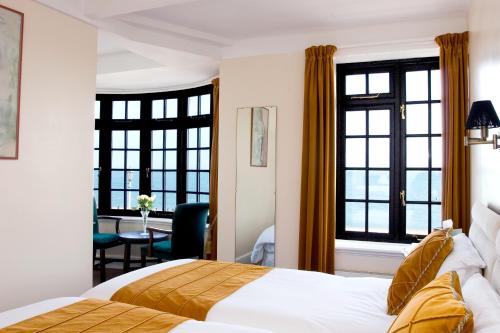 a hotel room with a bed and two windows at Royal Hotel (Adults Only) in Eastbourne