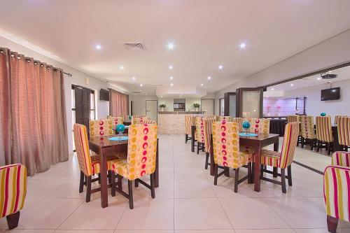 a dining room with tables and chairs with colorful chairs at Gecko Inn in Richards Bay