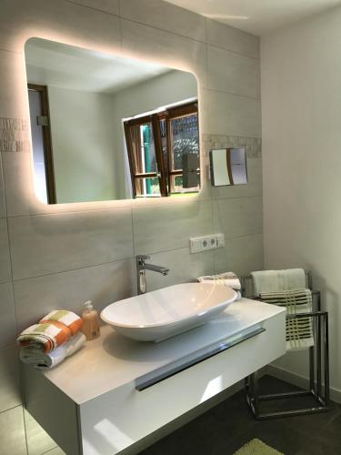 a bathroom with a white sink and a mirror at Hotel am Wiesenhang - Garni in Bad Kohlgrub