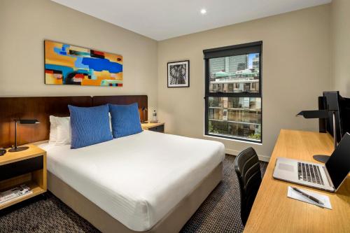 a hotel room with a bed and a desk with a laptop at Quest Docklands in Melbourne