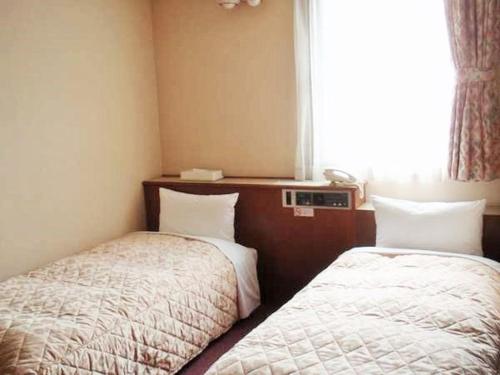 a hotel room with two beds and a window at Nishishinjuku Green Hotel in Tokyo