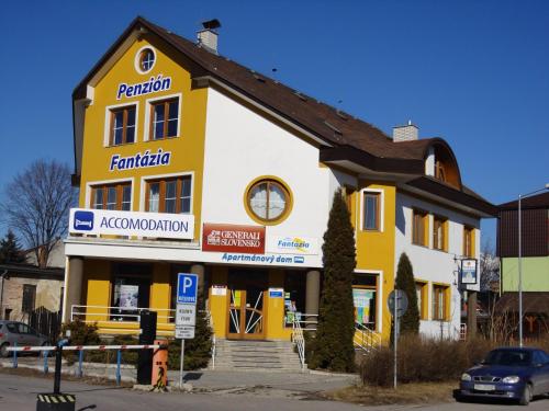 a yellow and white building with a car parked in front at Penzion Fantazia Poprad - Self check-in in Poprad