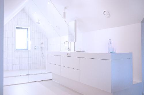 a white bathroom with a sink and a mirror at Maison Village in Noorbeek