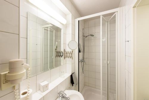 La salle de bains blanche est pourvue d'une douche et de toilettes. dans l'établissement Hotel Theophano, à Quedlinbourg