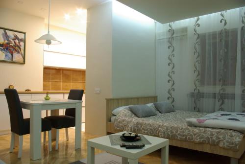 a bedroom with a bed and a desk and a table at Square Studio Apartment in Niš