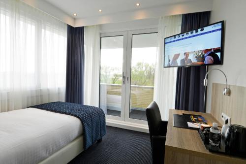 Habitación de hotel con cama, escritorio y TV. en Hotel De Zoete Inval Haarlemmerliede, en Haarlem
