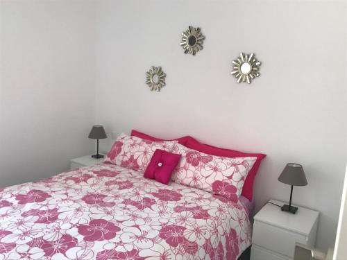 a bedroom with a pink bed and two mirrors on the wall at Vista Faro 39 in Maspalomas