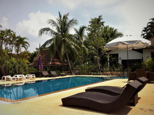 a swimming pool with lounge chairs and an umbrella at Baan Thai House in Phra Nakhon Si Ayutthaya