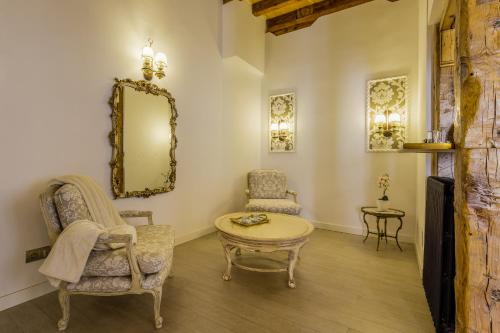 a living room with a chair and a table and a mirror at Oriente Palace Apartments in Madrid