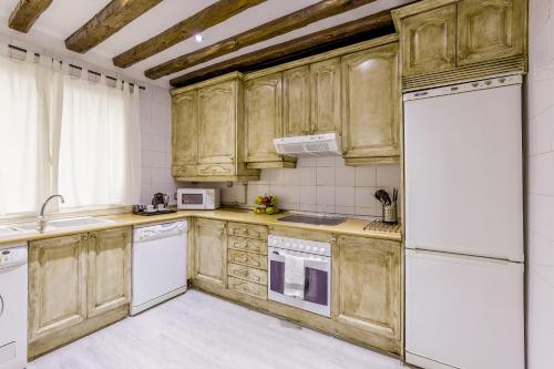 a kitchen with wooden cabinets and white appliances at Oriente Palace Apartments in Madrid
