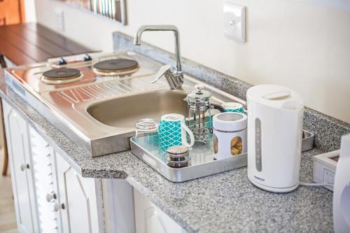 a kitchen counter with a sink with cups and a appliance at AnnVilla Guesthouse in Klerksdorp