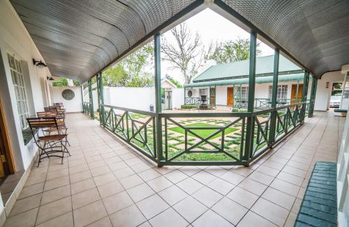 a covered porch with chairs and tables and a building at AnnVilla Guesthouse in Klerksdorp
