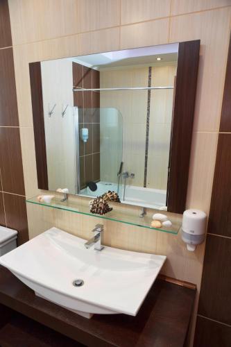 a bathroom with a sink and a large mirror at Gaia Palace in Mastichari