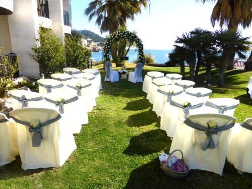 a row of tables with white chairs in the grass at Estela Barcelona in Sitges