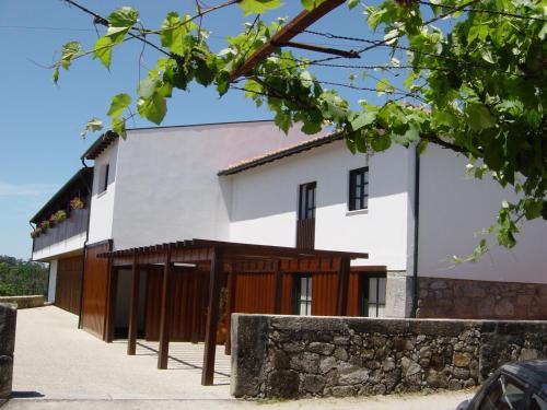 a white house with wooden doors and a stone wall at Quinta do Burgo - Nature Hotel in Amares