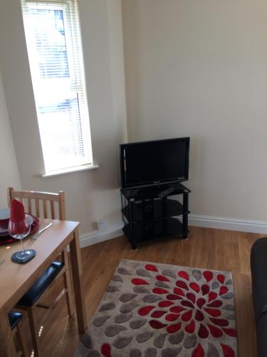 a living room with a television and a table and a rug at The Custards in Shanklin