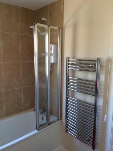 La salle de bains est pourvue d'une douche avec une porte en verre. dans l'établissement The Custards, à Shanklin