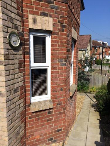 a brick building with a window and a clock on it at The Custards in Shanklin