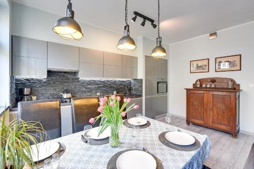 eine Küche mit einem Tisch mit Tellern und Blumen darauf in der Unterkunft Apartment Mariacka Exclusive in Danzig