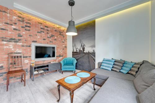 a living room with a couch and a brick wall at Apartment Mariacka Exclusive in Gdańsk