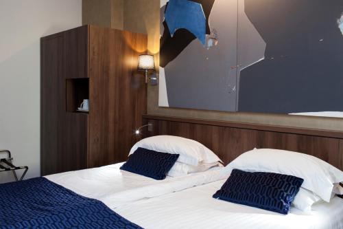 a bedroom with a bed with two blue pillows at Best Western Plus Monopole Métropole in Strasbourg