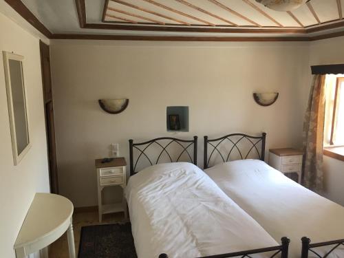 1 dormitorio con 1 cama con sábanas blancas y mesa en Elafotopos Hotel, en Elafotopos