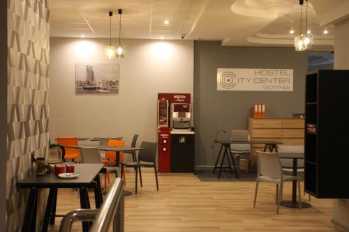 um restaurante com mesas e cadeiras e uma cozinha em Hostel City Center Gdynia em Gdynia
