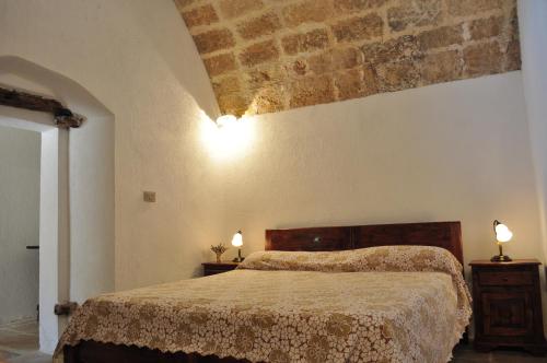 パトゥにあるMasseria San Nicolaのベッドルーム1室(ベッド1台、壁に照明2つ付)