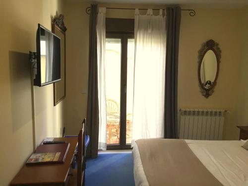 a bedroom with a bed and a mirror and a window at Hotel Arco San Vicente in Ávila