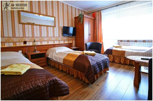 グダニスクにあるAbWentur Pokojeのベッド2台とテレビが備わるホテルルームです。