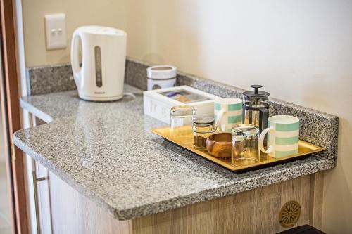 a counter with a tray with cups and a coffee maker at AnnVilla Guesthouse in Klerksdorp