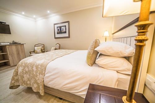 a bedroom with a large bed with white sheets and pillows at AnnVilla Guesthouse in Klerksdorp