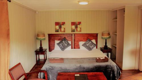 a bedroom with a large bed and two chairs at Magoebaskloof Getaway in Magoebaskloof
