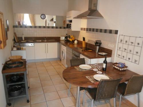 Il comprend une cuisine avec une table et des chaises en bois. dans l'établissement Maison de la Place, à Saint-Chinian